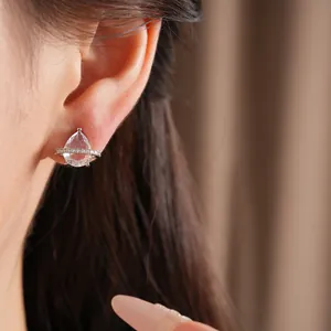 Gros plan d'une boucle d'oreille en zircon poire avec anneau planète sur l'oreille