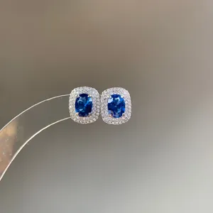 Close-up of royal blue oval stud earrings with sparkling double halo of stones