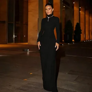 Robe longue noire élégante à manches longues et col roulé avec taille drapée raffinée.