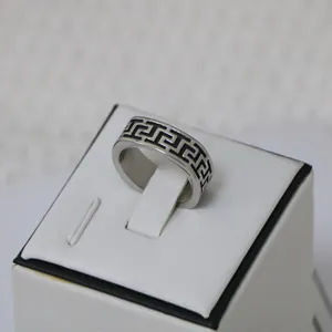Vintage silver titanium steel ring with black Greek key pattern for men shown on a display stand