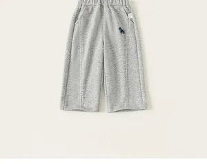Détail d'un pantalon de jogging gris pour enfant avec broderie de chien bleu marine
