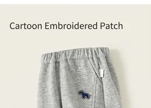 Gros plan d'un pantalon gris pour enfant avec broderie de chien bleu et texture douce