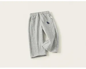Vue détaillée d'un pantalon de jogging gris pour enfant avec un petit patch animal bleu.