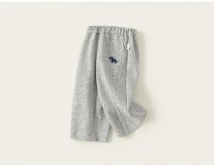 Gros plan d'un pantalon de survêtement gris confortable pour enfant avec broderie chien.