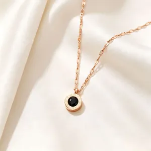 Macro detail of rose gold Roman numeral necklace with black crystal pendant on silk