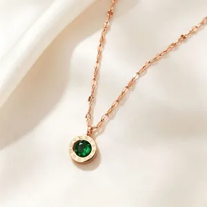 Detail of rose gold necklace featuring a green crystal pendant with Roman numerals.