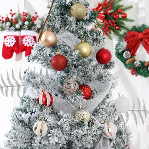 Assorted red and gold Christmas ball ornaments displayed on a white flocked holiday tree