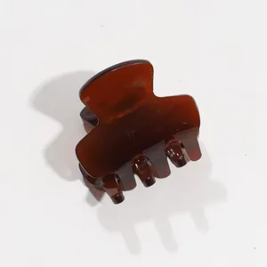 Detailed macro view of an amber brown acetate hair claw clip for elegant styling.
