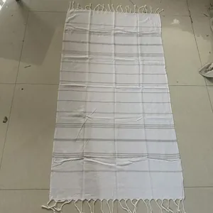 Full view of a white Turkish beach towel featuring grey stripes and elegant tassels.