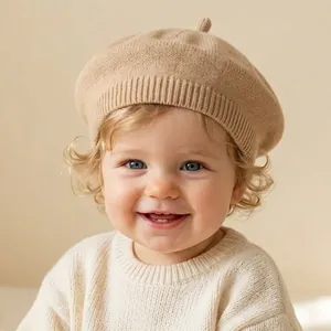 Close-up of a cute baby wearing a soft beige knitted beret and cream knitted sweater