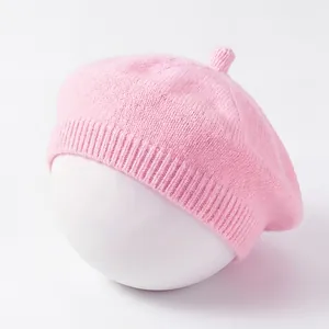 Close-up view of a soft pink knitted baby beret painter hat for early spring.