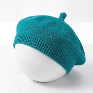 Detailed view of a soft teal knitted baby beret shown on a white spherical stand