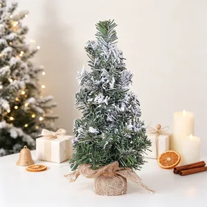 Detailed view of a miniature snow-covered Christmas tree with rustic burlap base