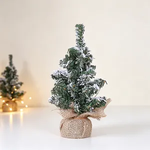 Detailed close-up of a mini snow flocked Christmas tree with burlap base for desktop decoration