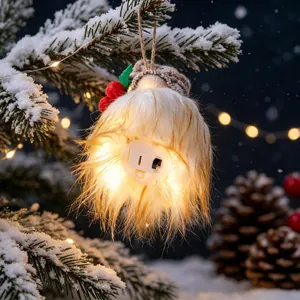 Glowing Christmas gnome ornament with knitted hat hanging on snowy pine tree branch