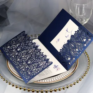 Luxury navy blue laser-cut wedding invitation card with elegant floral pattern on a plate.