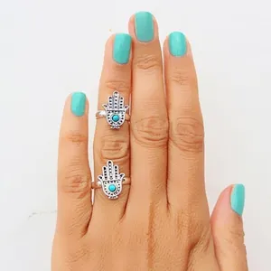 Detailed view of vintage Hamsa hand rings with turquoise stone worn on a model's hand