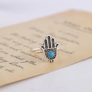 Detailed macro view of vintage Hamsa hand ring with turquoise stone and silver finish