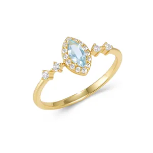 Close-up macro view of sky blue marquise topaz ring with 14k gold band and zircon halo