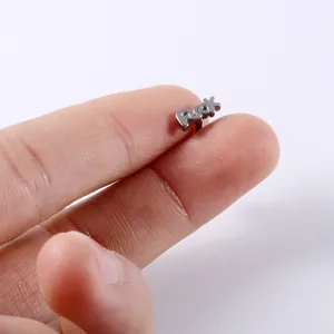 Macro view of a stainless steel tongue stud featuring a bold 'Fuck' letter design.
