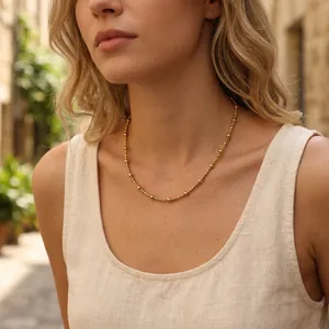 Detail view of a French style gold beaded necklace choker for women worn by a model.