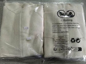 Detailed view of two white men's knit zip-up sweaters in their protective zip packaging