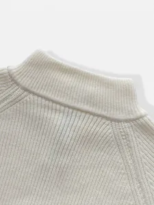 Close-up detail of the ribbed mock neck and textured knit of a white men's sweater.