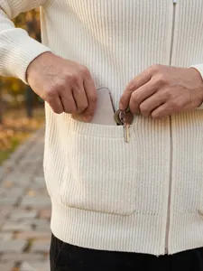 Detail shot of a white ribbed knit cardigan pocket holding a phone and keys