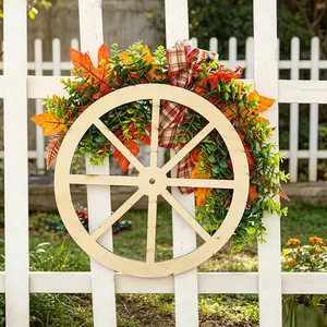 Decorative autumn wooden wheel wreath with maple leaves on a white fence for harvest.
