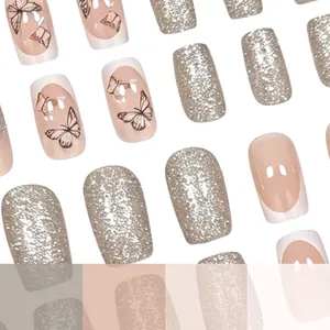Close-up of glossy press-on nails with butterfly motifs and champagne gold glitter