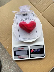 Handmade red crocheted heart pocket hug shown on a scale, weighing 11 grams.