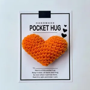 Detailed view of handmade orange crocheted heart pocket hug on its greeting card
