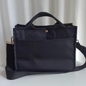 Multi-compartment black canvas mummy bag with handle and adjustable shoulder strap
