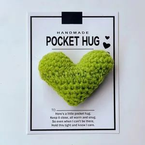 Detail view of a lime green handmade crocheted pocket hug heart with a white backing card.