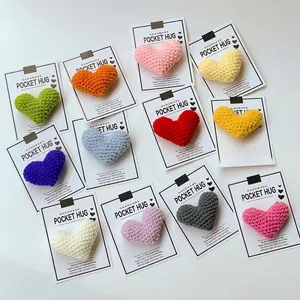 Detailed view of handmade colorful crocheted heart pocket hugs attached to white cards