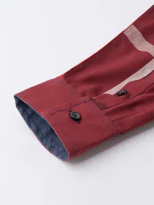 Détail d'un poignet de chemise en coton bordeaux avec motif à carreaux et boutons noirs.
