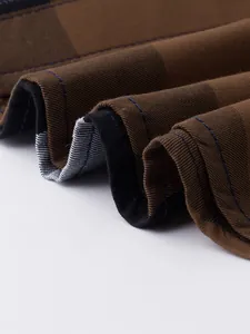 Gros plan sur le tissu de chemise en coton à carreaux marron et noir, couture bleue