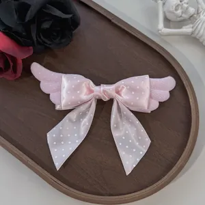 Détail d'un nœud à cheveux rose à pois avec des ailes en peluche, style Lolita