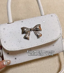Detailed macro shot of a white handbag featuring a 3D silver bow and star patterns.