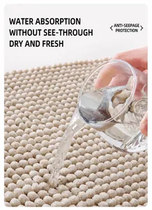 Nahaufnahme von Wasser, das auf eine saugfähige beige Badematte aus Chenille gegossen wird