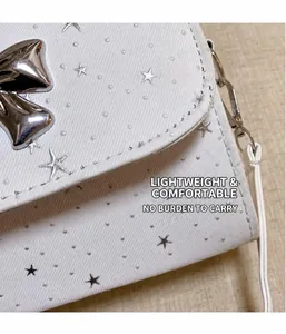 Close-up detail of a white crossbody bag featuring a silver bowknot and star patterns