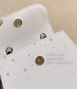 Close-up of the metal magnetic snap button on white star-patterned handbag detail