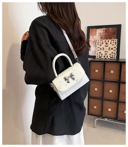 Elegant white small square handbag featuring a silver bow accent and slim shoulder strap