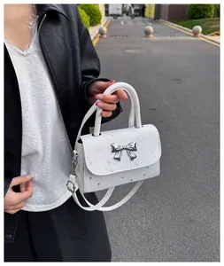 Fashionable woman holding a white star-patterned handbag with a metallic silver bow charm.