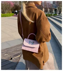 Stylish pink small square handbag with silver bow detail and star prints shown in outdoor use