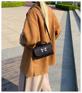 Stylish black crossbody bag with silver bow detail and star pattern in lifestyle use