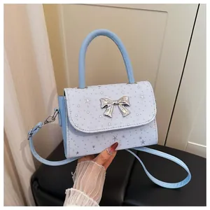 Close-up detail of a light blue fashion handbag featuring a silver bow and star pattern