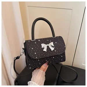 Detailed view of a black star-patterned handbag with a silver bow and top handle