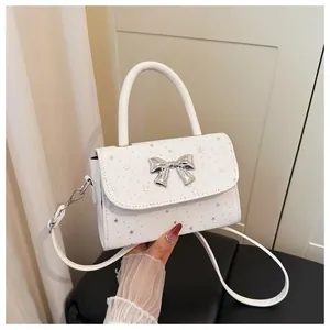 Detailed view of a white bow handbag with silver star pattern and shoulder strap