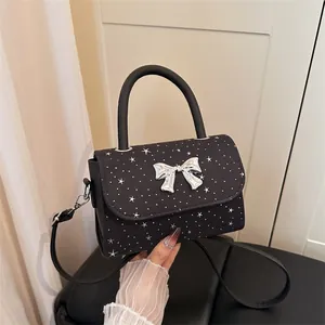 Elegant black bow handbag with silver star patterns, featuring a stylish top handle.
